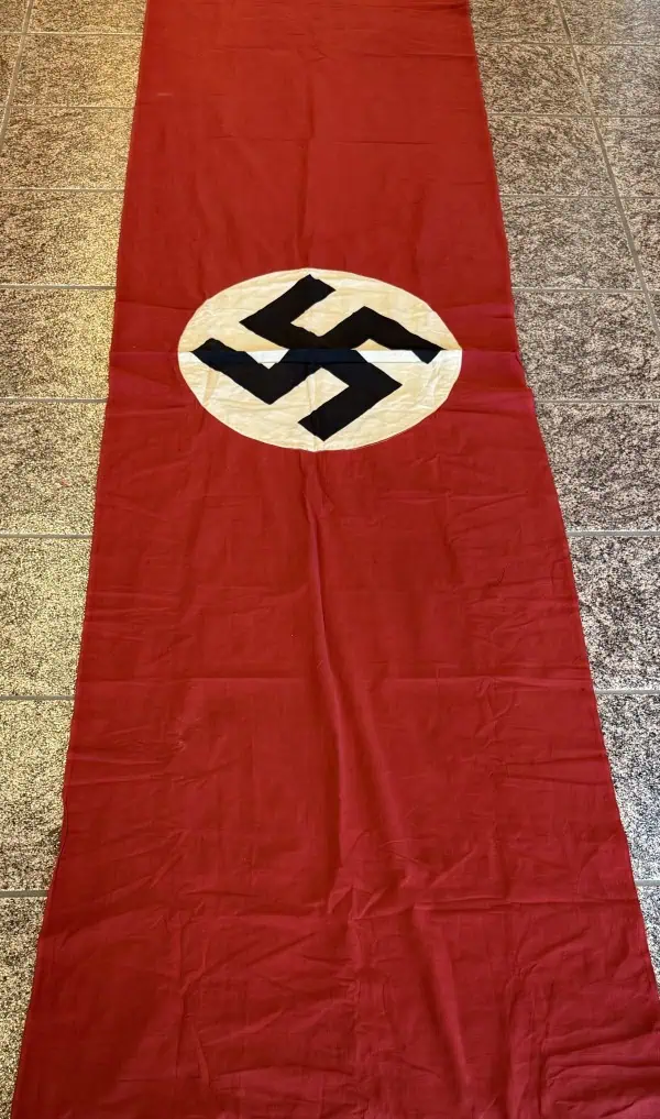 Swastika Nazi flag displayed on the floor with a red background and white circle.