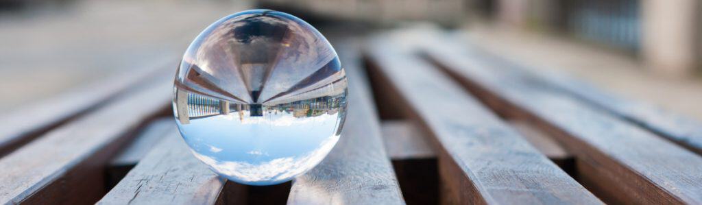 Insightful reflection of urban landscape inverted through the glass sphere on a wooden bench. Perfect for business growth, innovation, and media brand visual storytelling.