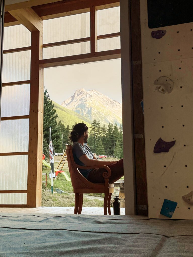Person sat looking out towards the mountains at a climbing wall in Switzerland.