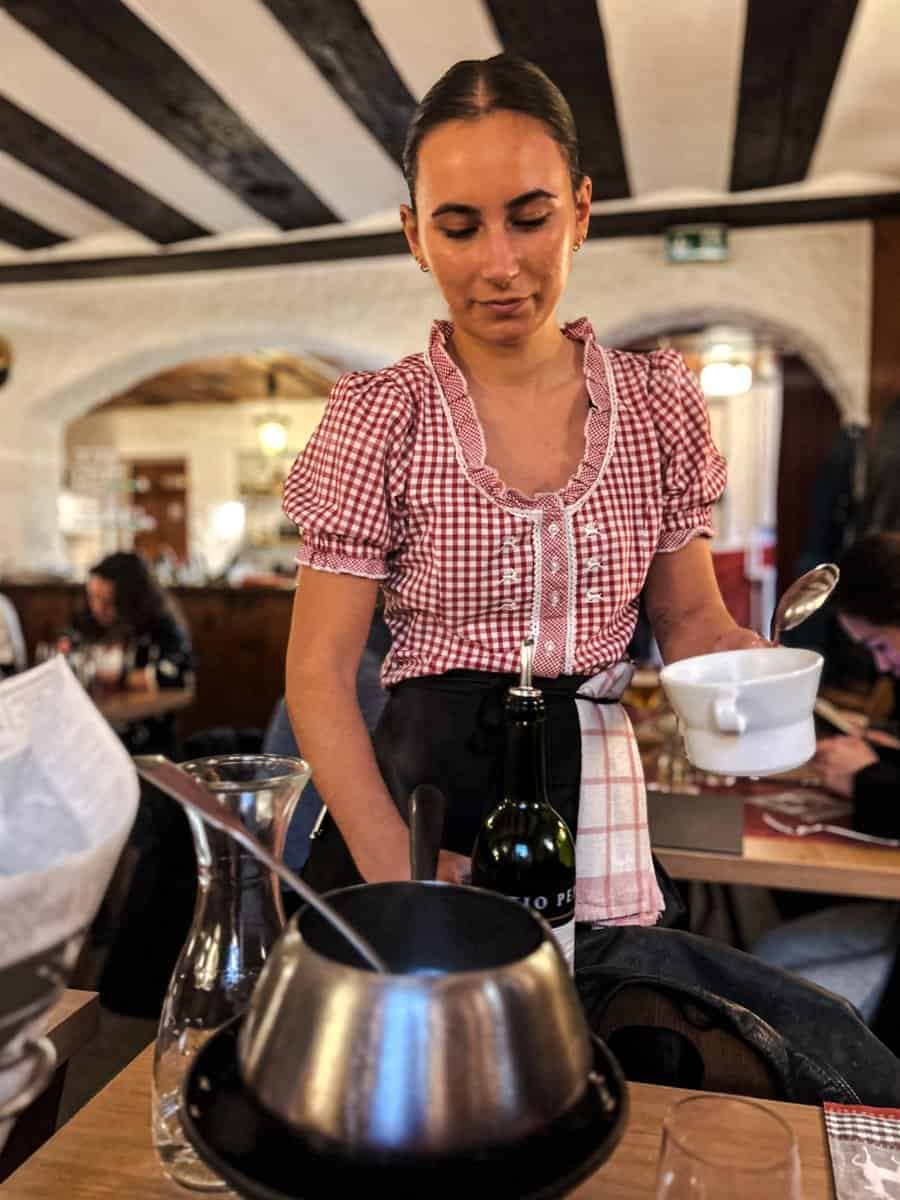 Waitress serving fondue broth at the Whymperstube, Zermatt.