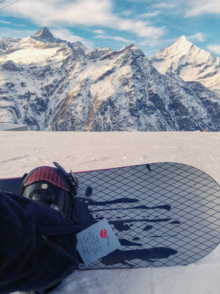 The end of a snowboard in front of the Swiss Alps.