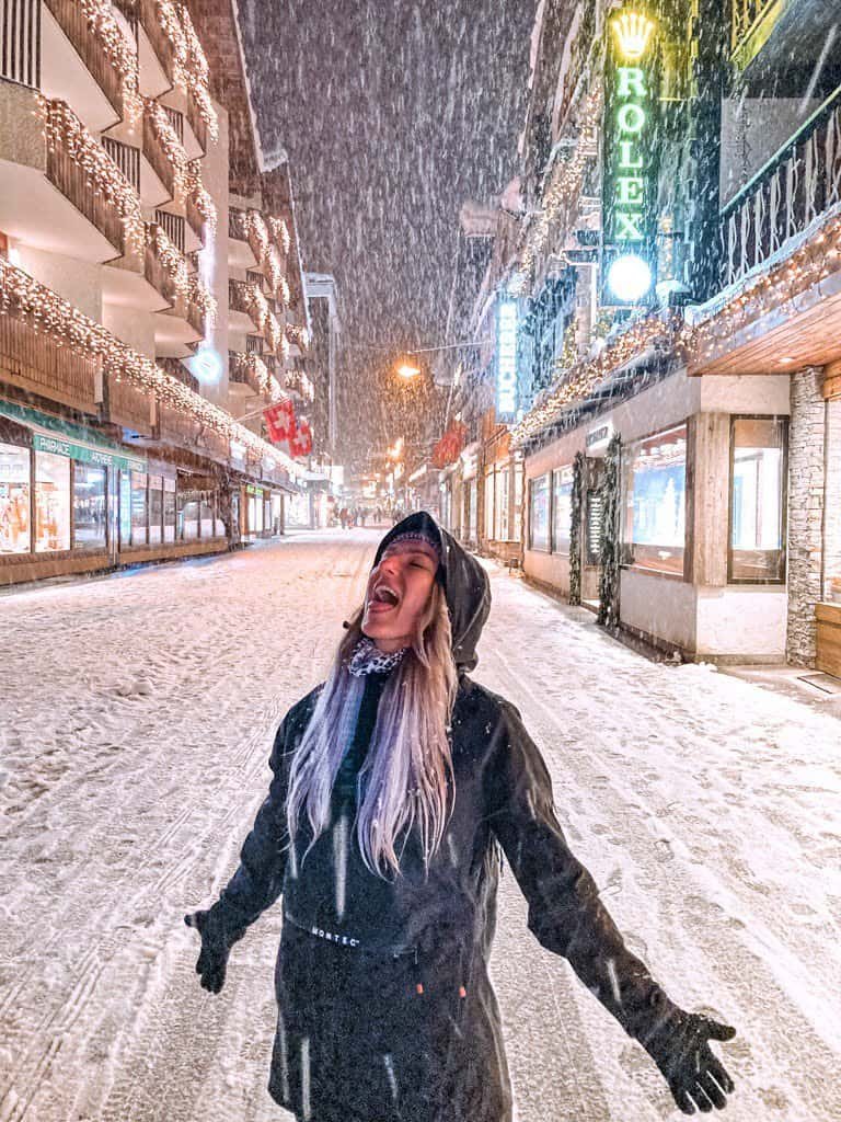 A women catching snowflakes on Zermatt high street.
