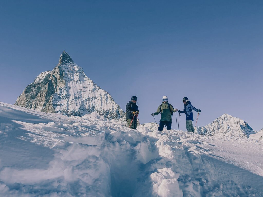 Three Ski tourers stood in front of the Matterhorn among lots of snow.