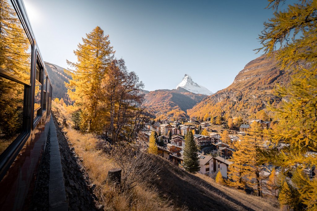 Trees, Zermatt village and the Matterhorn in a golden autumn glow.