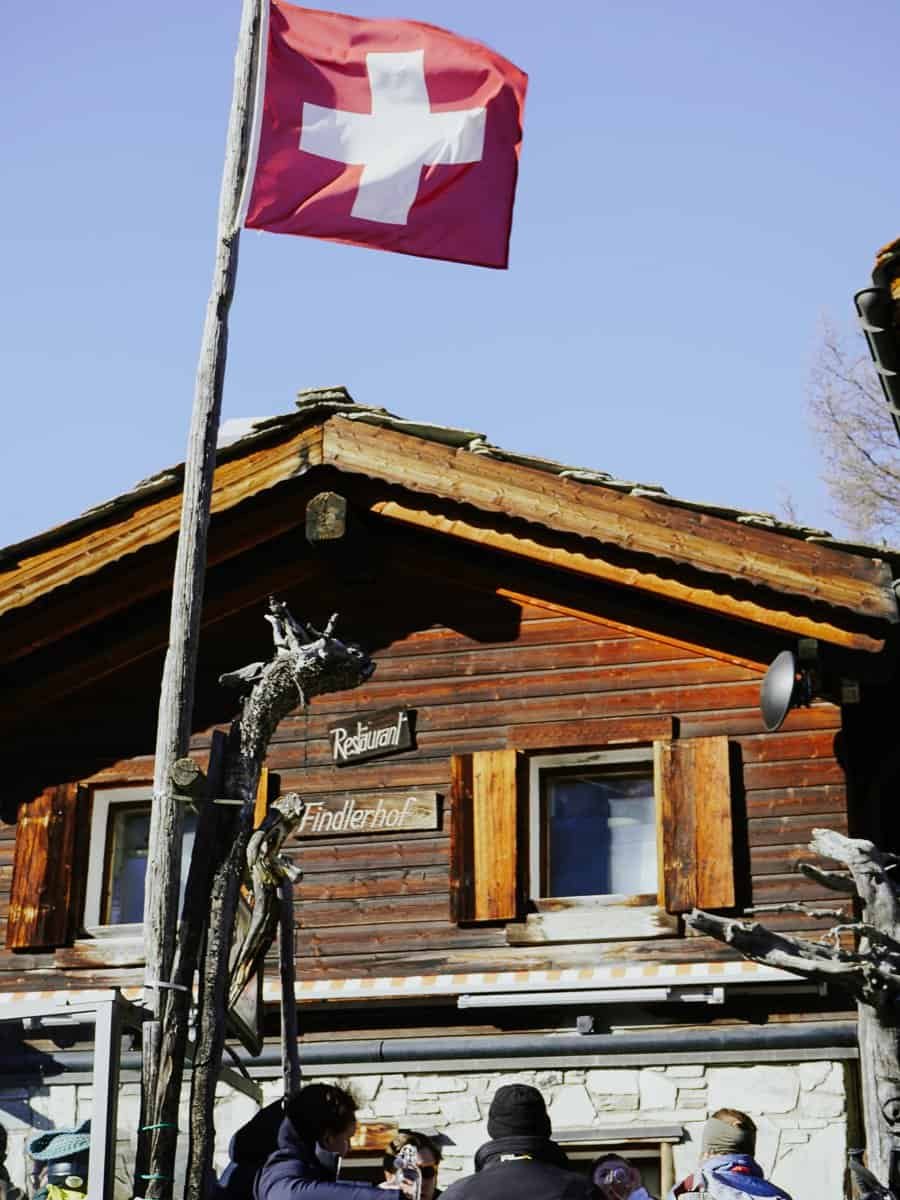 Swiss flag outside of a wooden mountain hut in Zermatt.