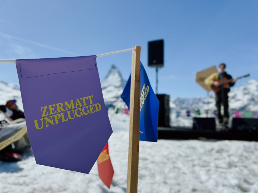 Zermatt Unplugged flag pole in front of a musician playing in the snow.