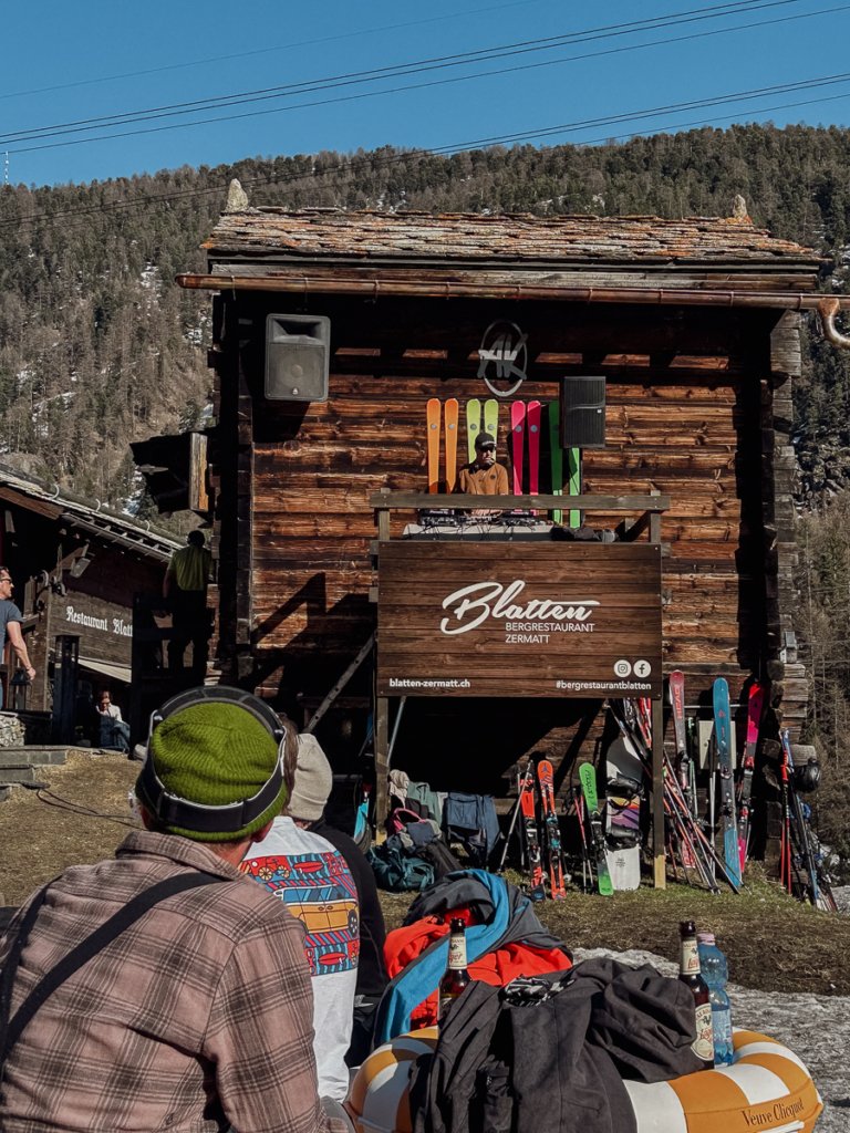 DJ playing in front of brightly coloured skis, outdoors at Restaurant Blatten in Zermatt.
