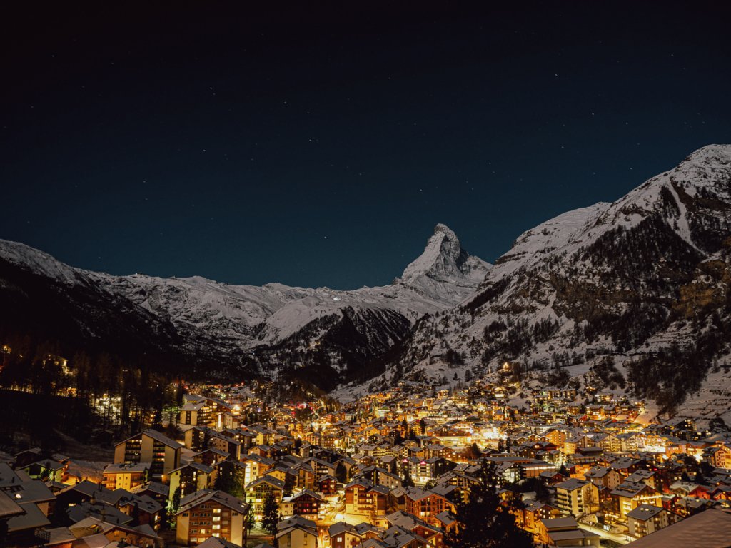 Buildings glowing at night and the Matterhorn.