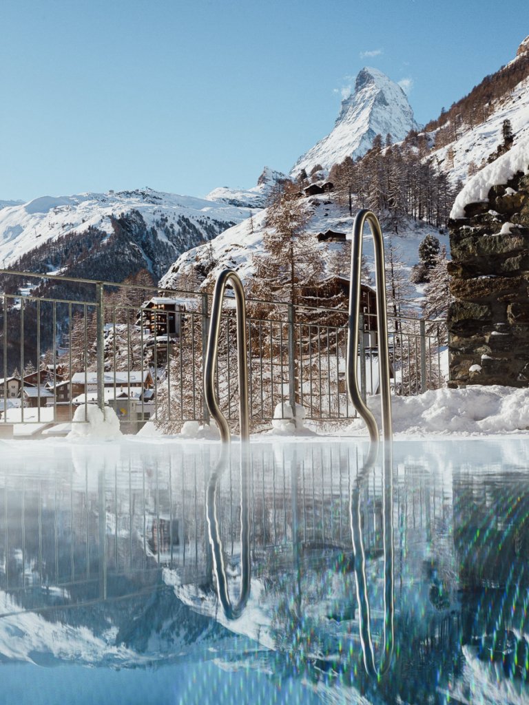 A calm Omnia pool surrounded by the snow covered Swiss Alps and the Matterhorn.