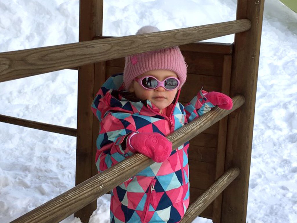 Little girl playing in the snow-covered park with Alpine Nanny in Zermatt Switzerland