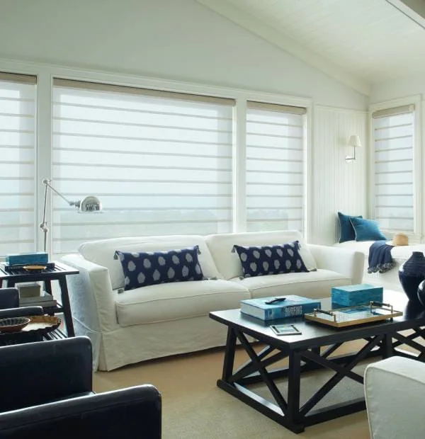 Bright beach-inspired living room with white window treatments and navy accent pillows.