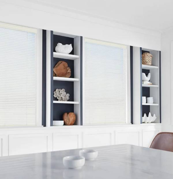 Decorative shelving with modern ceramics, art pieces, and natural elements in a bright room.