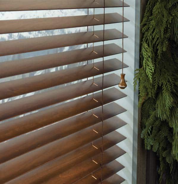 Wooden horizontal blinds with lush green plant wall on side.