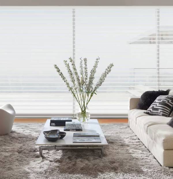 Bright living room with white sofa, coffee table, and vase with flowers.