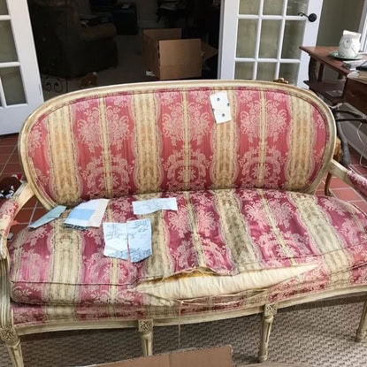 Vintage pink and cream upholstered sofa featuring ornate fabric pattern, perfect for traditional home decor.
