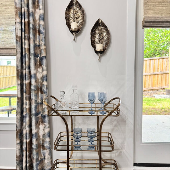 Stylish gold bar cart with glassware and decorative wall art.