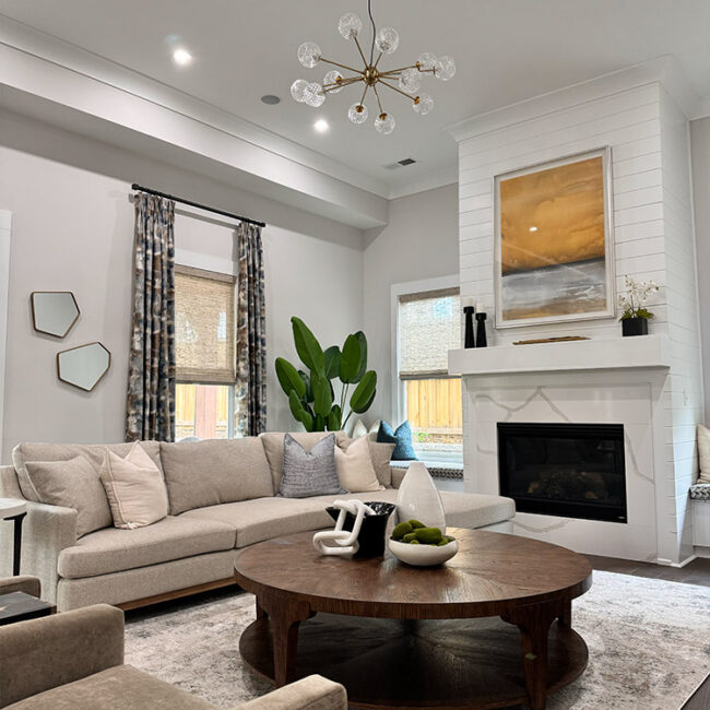 Bright living room with beige sofa, fireplace, and large windows with curtains.