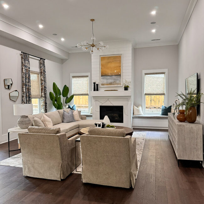 Bright living room with beige sofas, fireplace, and large windows.
