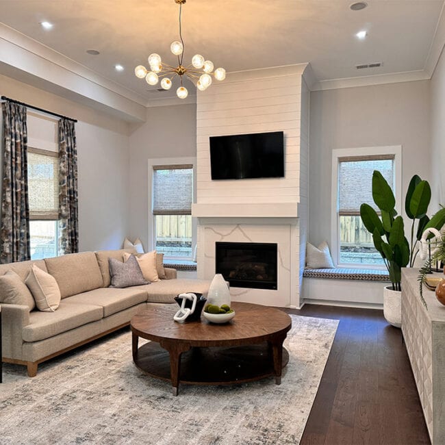 Bright living room with beige sofa, fireplace, and large windows with curtains.