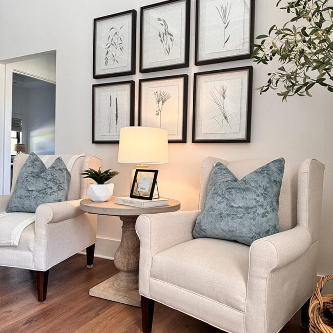 Cozy living room with two armchairs, side table, and botanical wall art.