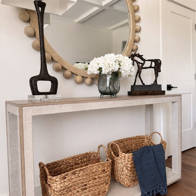 Decorative mirror, flowers, and baskets in a stylish entryway.