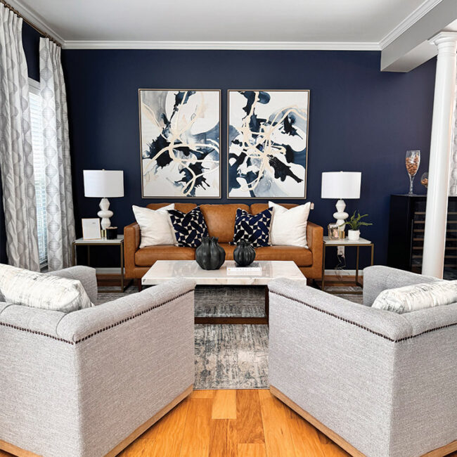 Stylish living room with navy wall, gray sofas, and abstract art.