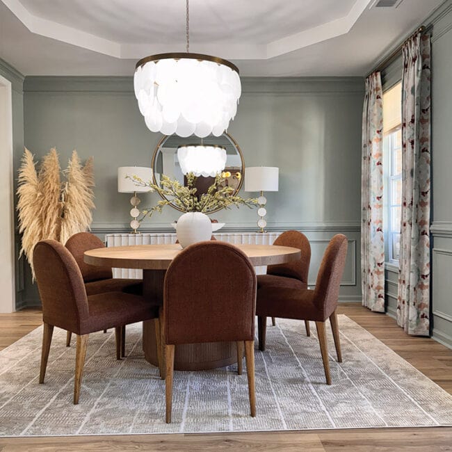 Stylish dining room with round table, velvet chairs, and modern chandelier.