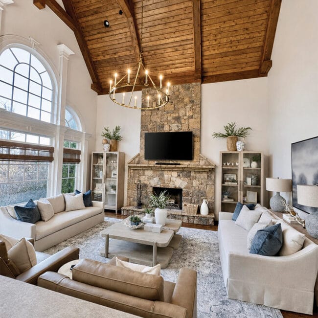 Spacious living room with high vaulted wooden ceiling and large windows.