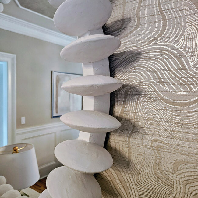 Contemporary white stone sculpture with smooth, rounded shapes on a textured surface.