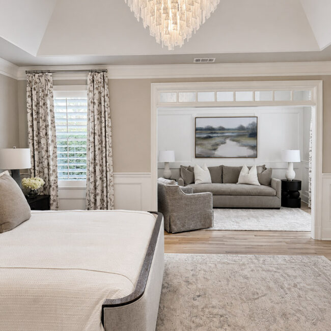 Bright living room with chandelier, sofa, and large windows with curtains.