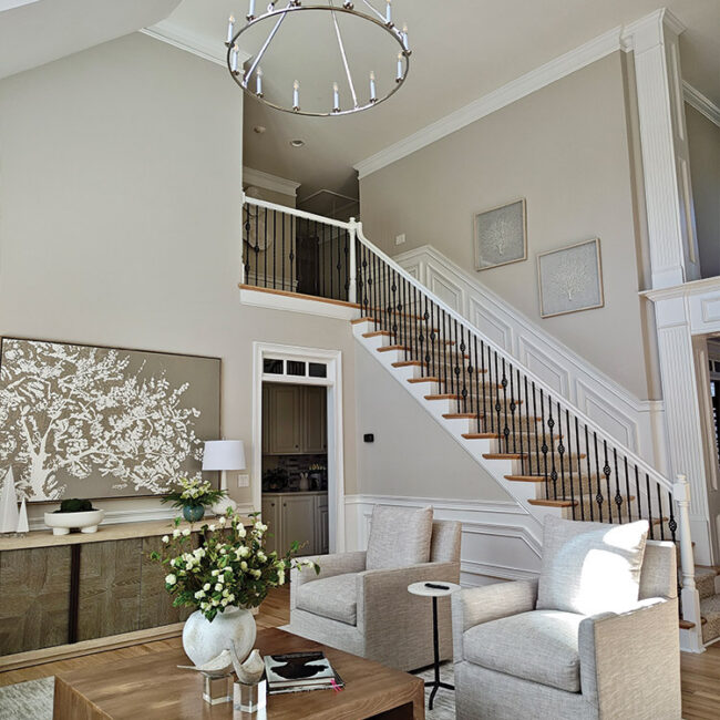 Bright living room with staircase, chandelier, and modern decor.