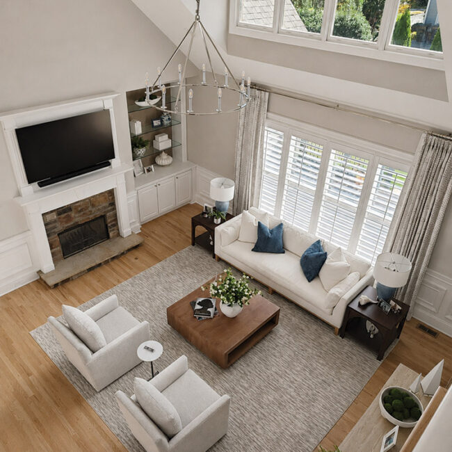 Spacious living room with large windows, white sofa, armchairs, and a fireplace.
