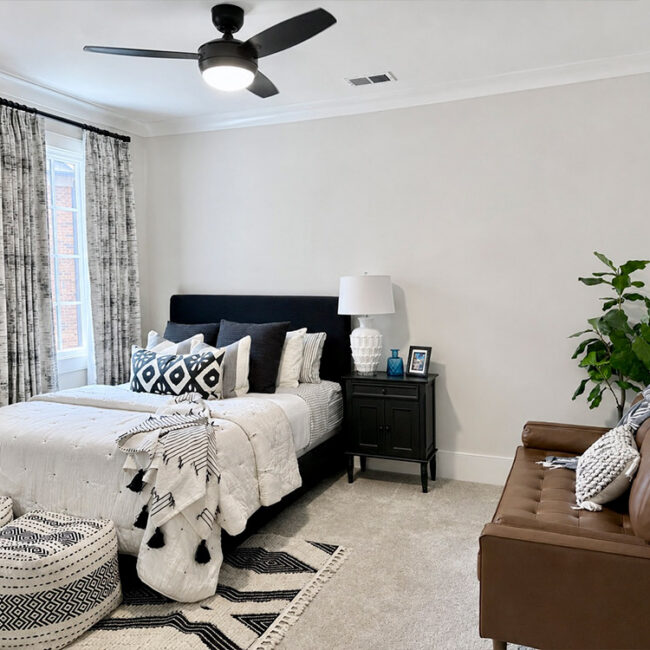 Bright bedroom with large window, bed, and stylish furniture.