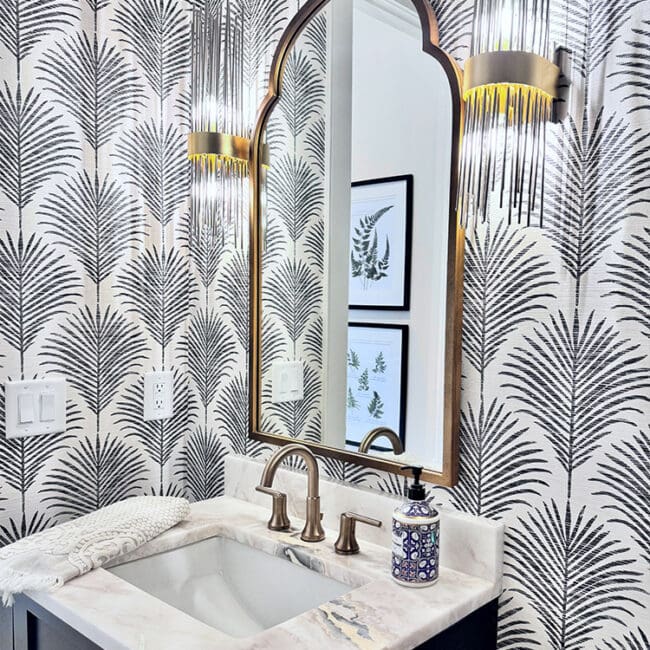 Decorative mirror with gold accents above a marble sink in a stylish bathroom.