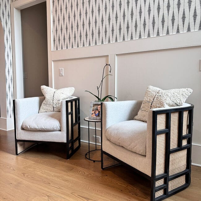 Two stylish armchairs with cushions and a small side table in a contemporary living room.