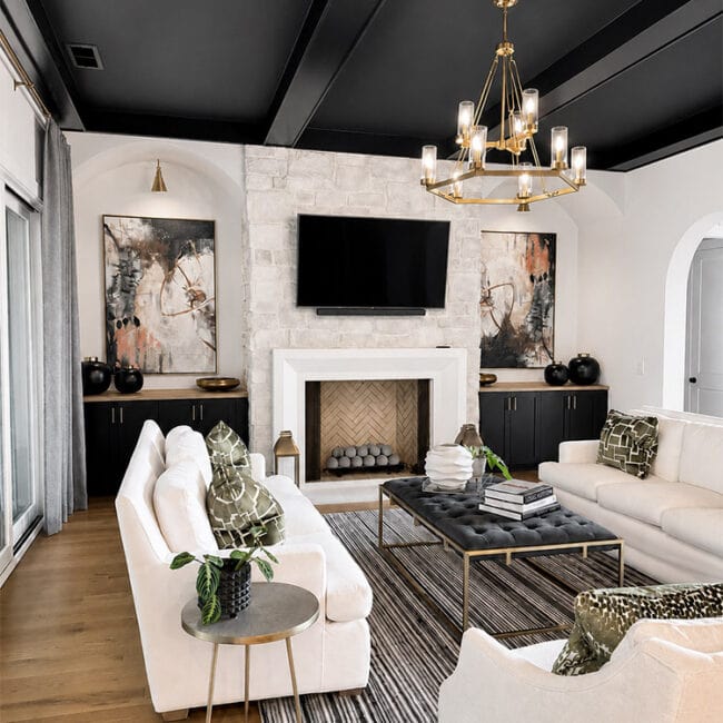 Elegant living room with white sofas, black accents, and a fireplace.