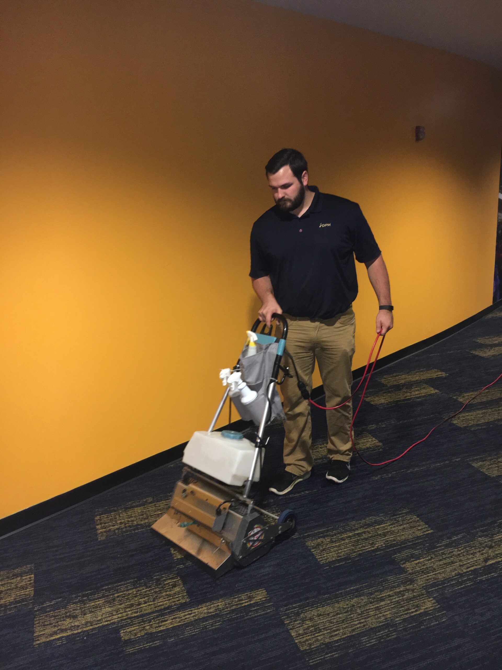 A man cleaning carpet in a commercial office using carpet cleaning machine. Careers at DPM Surface Care