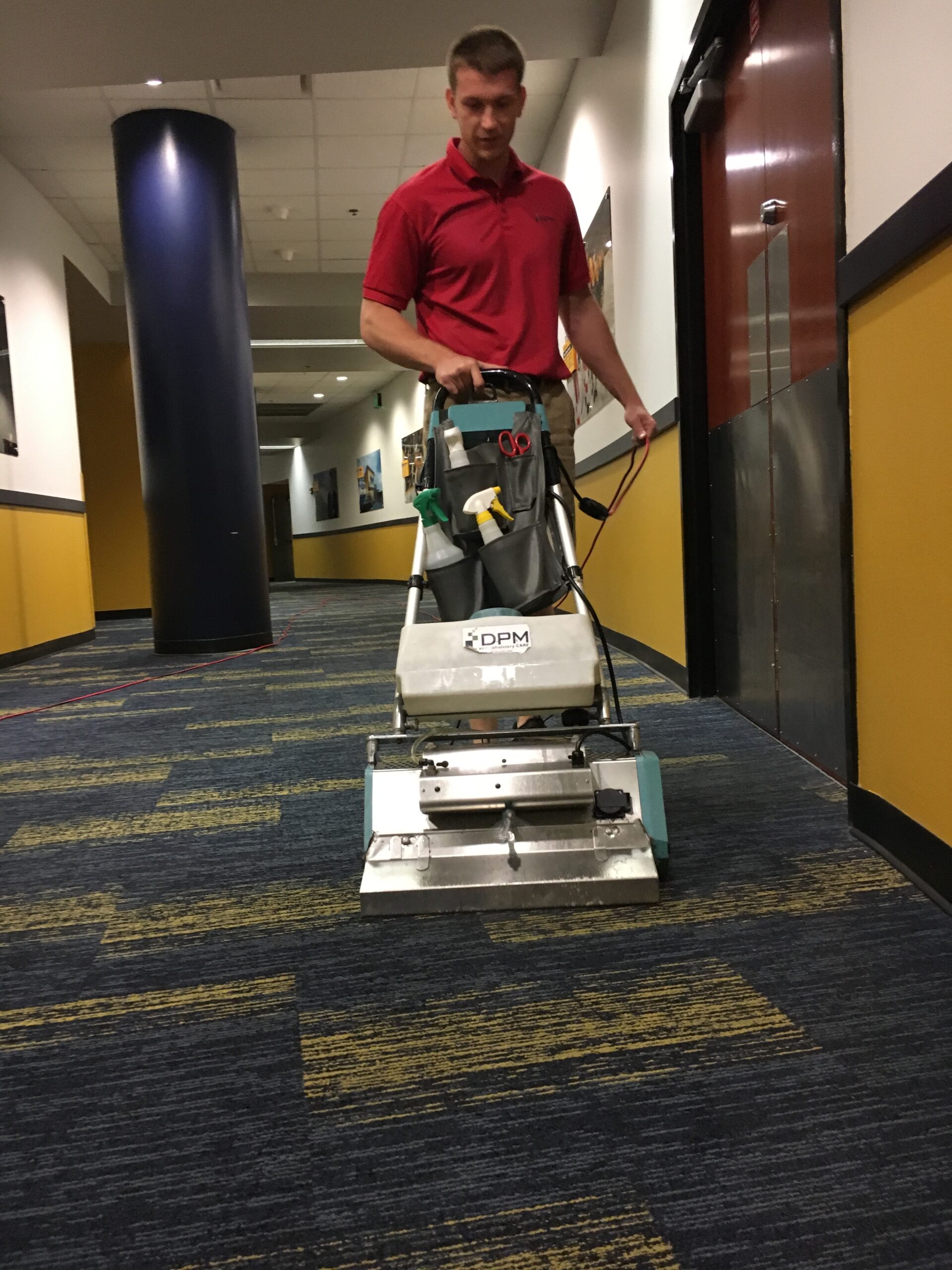 A man cleaning carpet in a commercial office using carpet cleaning machine. DPM Surface Care