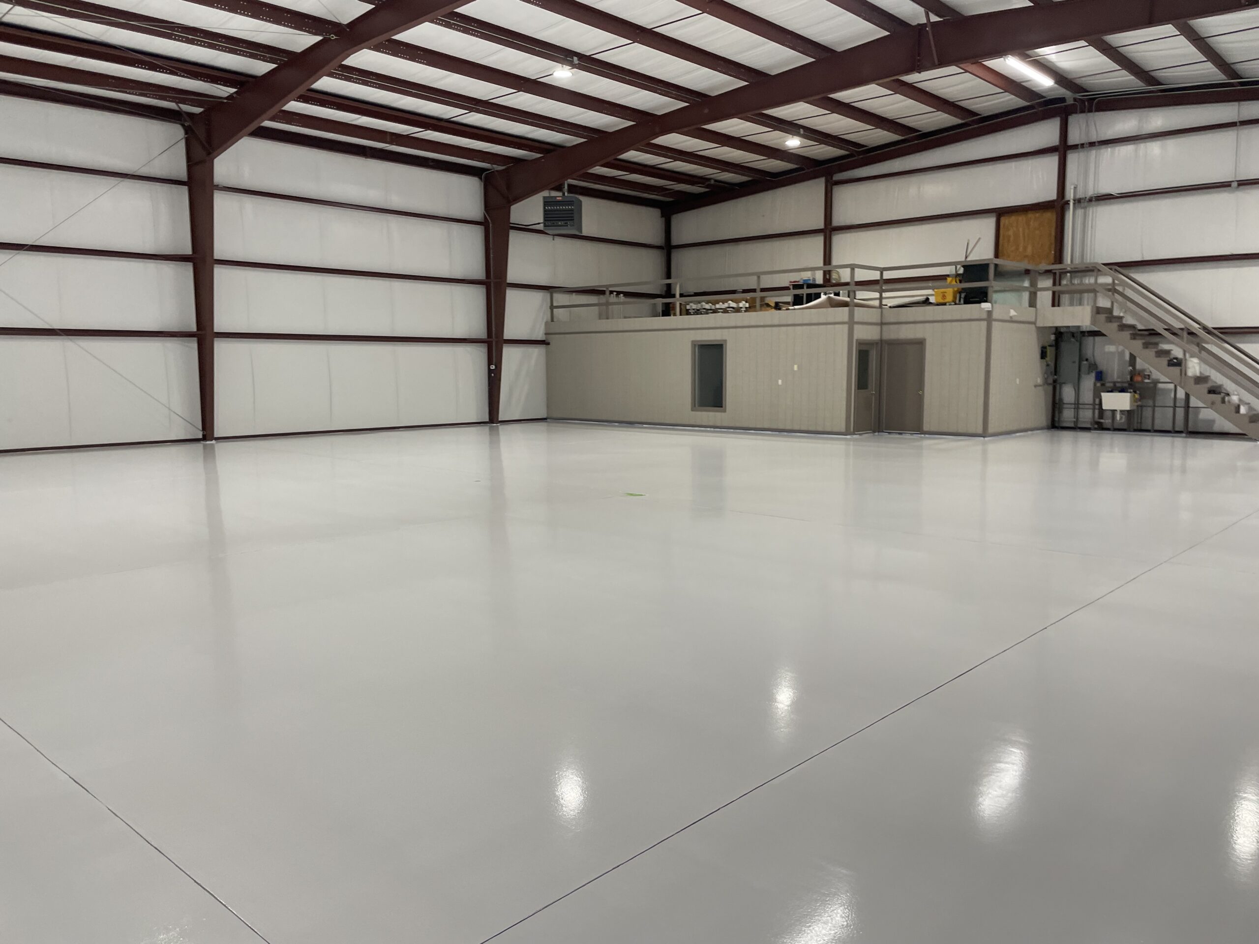 A spacious room with an epoxy coating floor, and a loft. DPM Surface Care