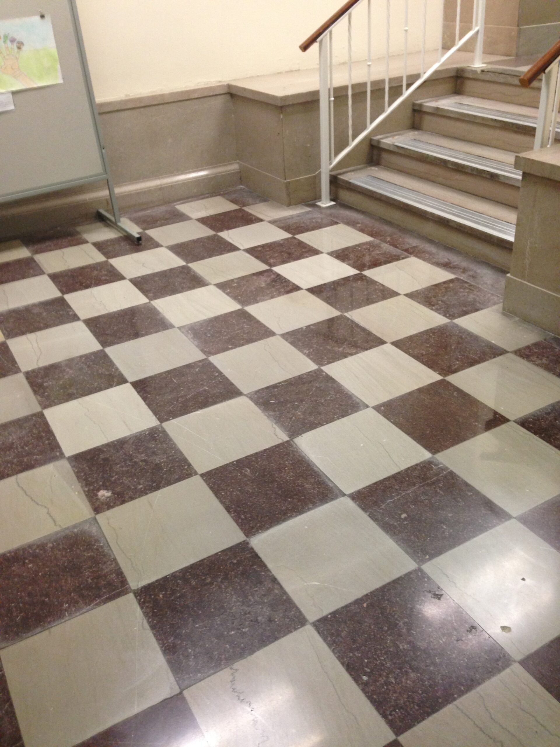 A dusty and worn, tiled natural stone floor with a checkered pattern, before cleaning. DPM Surface Care