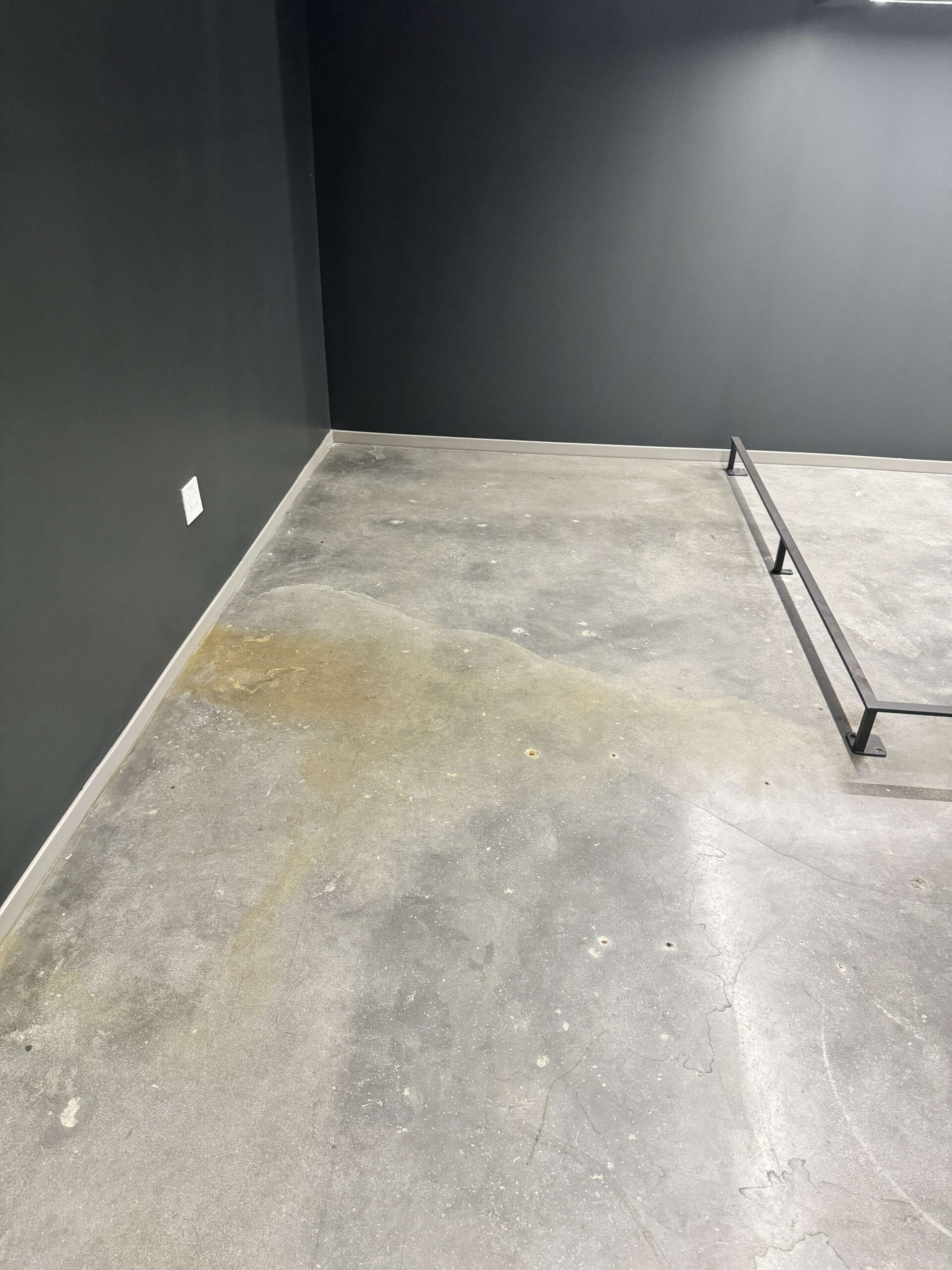 A concrete floor with a huge water stain, before cleaning. DPM Surface Care