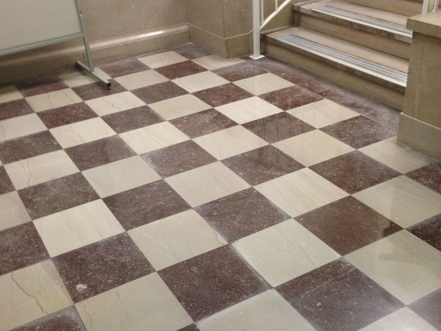 dpm-surface-care-natural-stone-before-img A dusty and worn, tiled natural stone floor with a checkered pattern, before cleaning. Surface renewal. DPM Surface Care