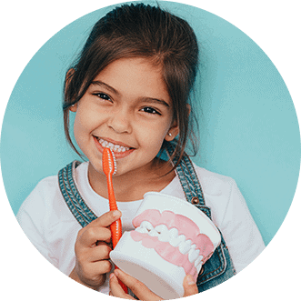 Girl child smiling against colored background with toothbrush | Armin Dental Associates