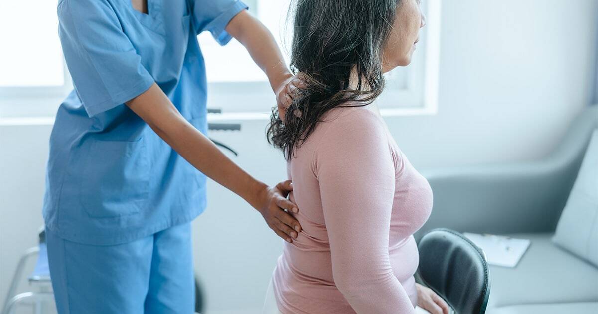 Back pain examination by healthcare professional at medical clinic.