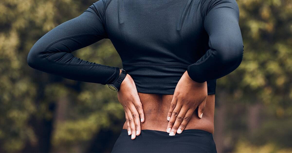 Back pain relief in athletic woman outdoors, sports injury prevention, chiropractic care, Dr. Rebecca McAllister.