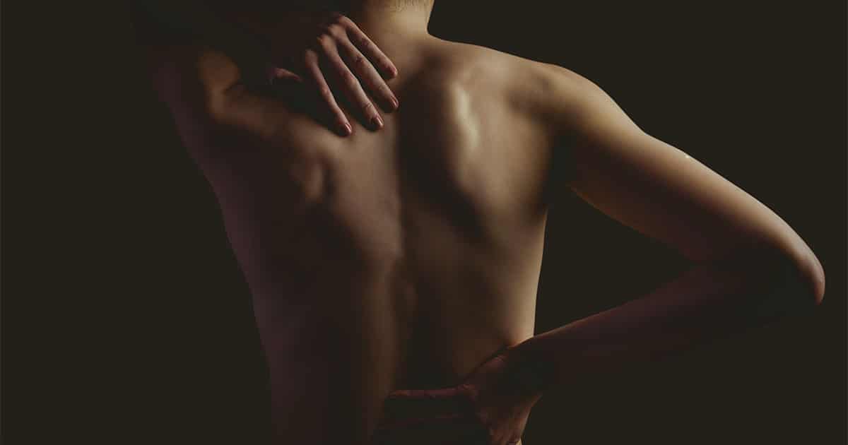 Elegant portrait of a woman with soft lighting, highlighting her bare shoulders and artistic pose for wellness imagery.