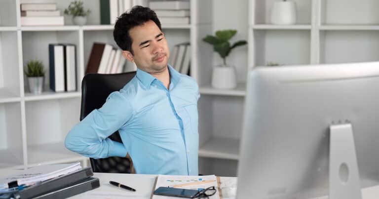 Back pain relief from office ergonomics, man experiencing discomfort at work.