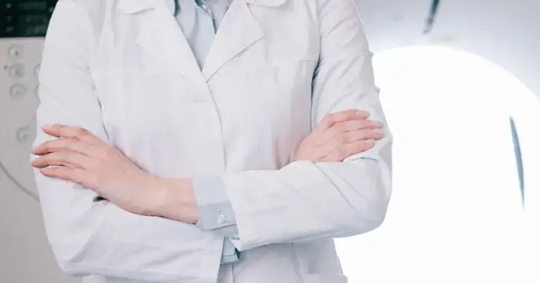 Healthcare professional in white coat with crossed arms, emphasizing back pain.
