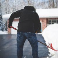 Shoveling snow in front of a house during winter in Canada.
