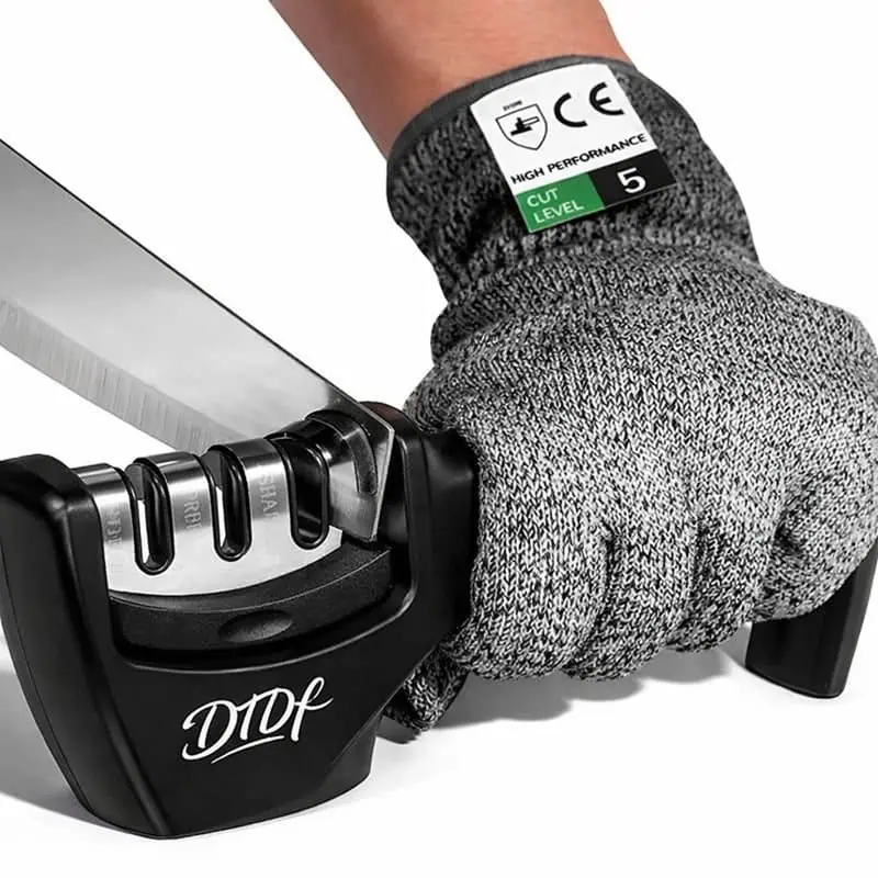 Hand wearing a cut-resistant glove using a 3-stage knife sharpener to sharpen a kitchen knife